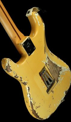 an old yellow electric guitar with some paint on it