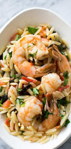 shrimp orzo with tomatoes and olives in a white bowl