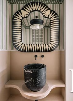 a black and white sink sitting under a mirror in a bathroom next to a shelf