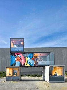 two people are sitting in the windows of a building that has been painted with colorful images