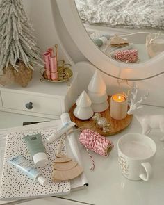 a vanity with various items on it and a christmas tree in the mirror behind it