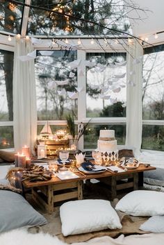 a living room filled with lots of furniture and pillows on top of a floor next to windows