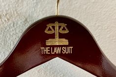 the law suit hanger has a scale on it's back and gold lettering that reads, the law suit