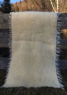 a white fur pillow sitting on top of a wooden fence