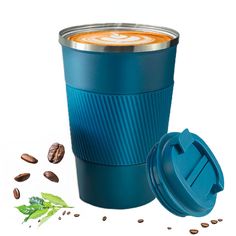 a blue coffee cup next to some nuts and leaves on a white background with the lid open