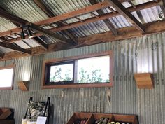 the inside of a building that has some shelves with wine bottles on it and two windows