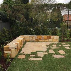 a stone bench sitting on top of a lush green field next to a garden area