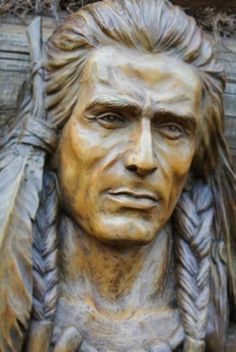 a close up of a statue of a man with feathers on it's head