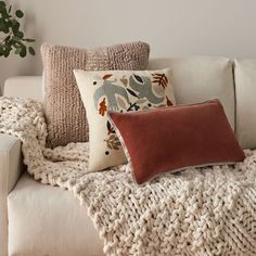 pillows on a couch with the words west elm written in black and white above them