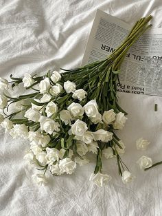 some white flowers and an open book on a bed