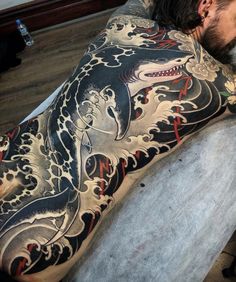 a man laying on top of a table covered in tattoos