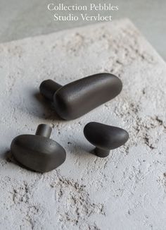 three pieces of black metal sitting on top of a white stone slab with the words collection pebble studio vervoet