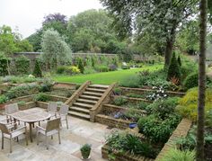 an outdoor patio with steps and tables surrounded by greenery