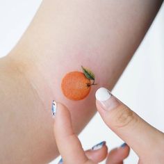 a woman's arm with an orange painted on it