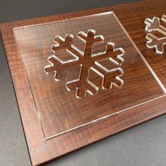 two metal snowflakes sitting on top of a wooden table