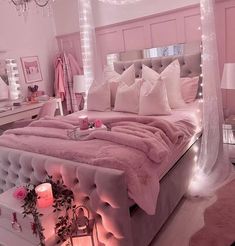 a bed with pink sheets and pillows on top of it in a room filled with lights