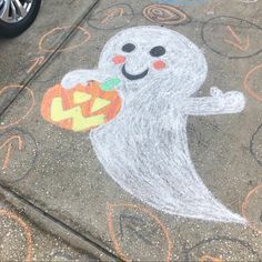 a chalk drawing of a ghost holding a jack - o - lantern on the sidewalk