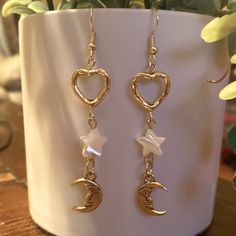 a pair of earrings with heart, moon and stars hanging from them on a table