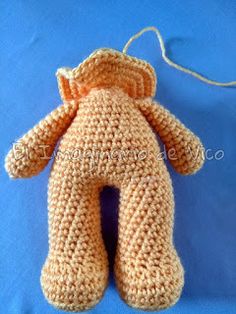 a crocheted teddy bear sitting on top of a blue surface with a white cord