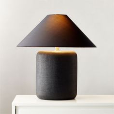 a black table lamp on top of a white dresser with a brown shade over it