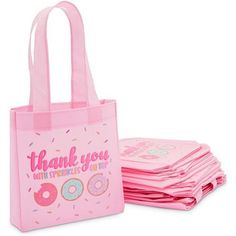 a pink bag with donuts on it sitting next to stacks of pink napkins