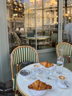 the table is set with coffee and croissants for two people to enjoy