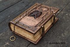 an old book with a skeleton on it sitting on a wooden floor next to a key