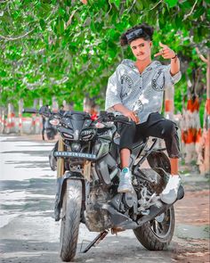 a man sitting on top of a motorcycle giving the peace sign with his right hand