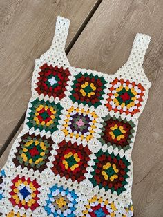 a crocheted bag sitting on top of a wooden floor next to a piece of wood