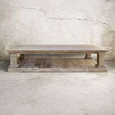 a wooden bench sitting in front of a cement wall