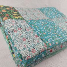 a close up of a piece of cloth on a white surface with flowers and leaves