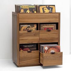 a wooden shelf with several drawers and cd's in it