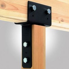 two black brackets are attached to the side of a wooden structure with metal rivets