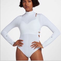 a woman in a white bodysuit with her hands on her hips