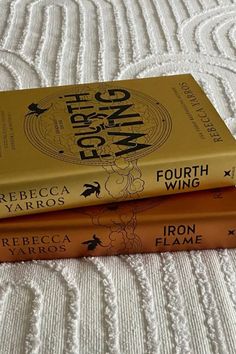 three books sitting on top of a bed next to each other in front of a white bedspread