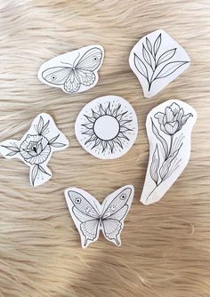 six stickers with flowers and butterflies in them on a wooden surface, one has a sunflower