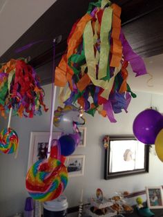 colorful streamers and balloons hanging from the ceiling in front of a mirror with pictures on it