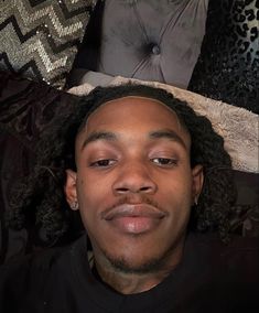 a close up of a person laying on a bed with pillows and blankets behind him