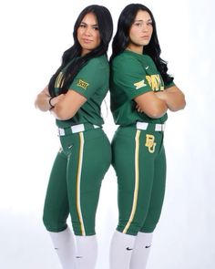 two women in green and white uniforms posing for the camera with their hands on their hips