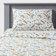 an image of a bed with dragonflies on the sheets and pillow cases in blue, yellow and white