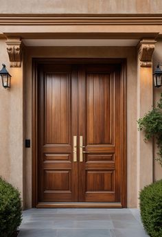 two wooden doors in front of a tan stucco building with light fixtures on either side