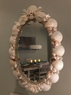 a mirror hanging on the wall above a table with chairs and candles in front of it