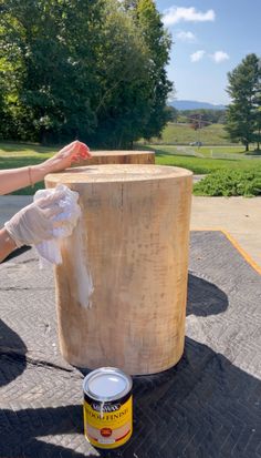 a can of paint sitting on top of a table next to a large wooden stump