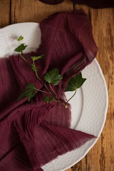 a white plate topped with a piece of cloth next to a red napkin on top of a wooden table