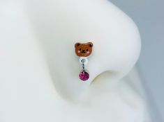 a bear earring with a pink crystal bead hanging from it's side