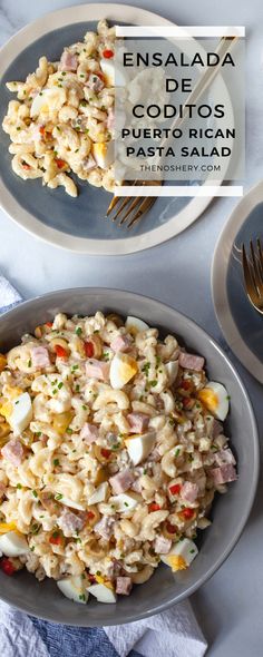 two plates filled with pasta and vegetables on top of a white table cloth next to silverware