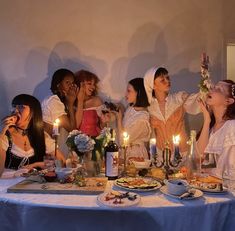 a group of women sitting around a table with food and candles