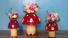 three vases with flowers in them sitting on a wooden table next to a blue wall