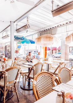 the inside of a restaurant with wicker chairs and umbrellas hanging from the ceiling