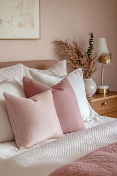 a bed with pink and white pillows on it